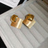 Gold Geometric Square Earrings – Stylish gold earrings featuring a mix of polished and brushed square elements, displayed in a jewelry box
