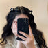 Woman wearing two black pearl-decorated hair clips while taking mirror selfie