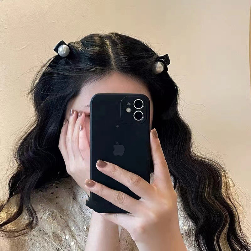 Woman wearing two black pearl-decorated hair clips while taking mirror selfie