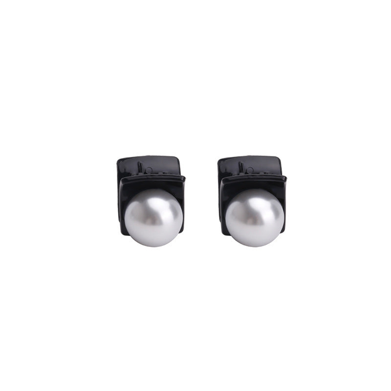 Product photo of black mini hair clips with large white pearl centers on white background