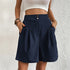 Model wearing navy blue pleated shorts with white crop top, showing classic tailored silhouette