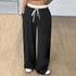 Close-up of black drawstring pants with white waistband and side pockets
