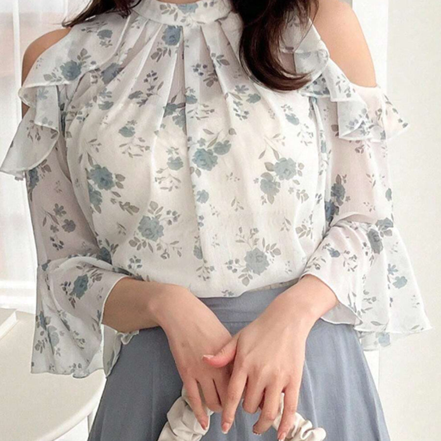 Woman in floral chiffon cold shoulder blouse with high neck and ruffles