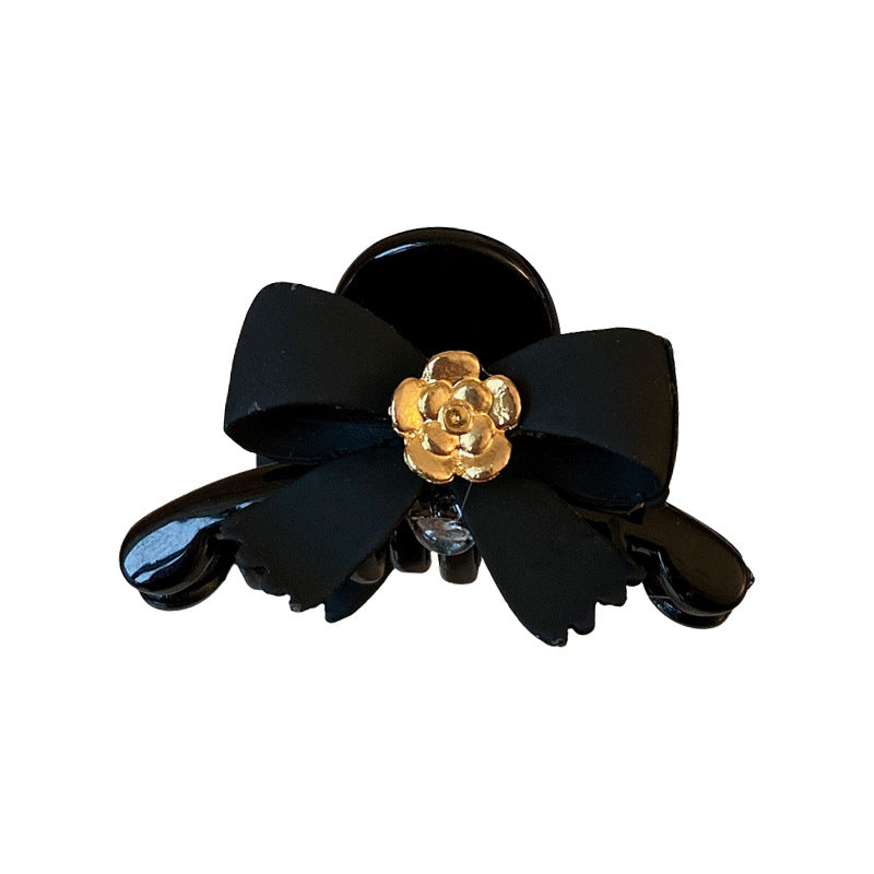 Product photo of black bow hair clip with gold camellia accent