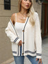 Cream cable knit cardigan with navy trim, styled with white top and wide-brim hat for casual elegance