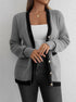 Close-up of gray knit cardigan with black trim and gold buttons, showing side pockets and detailed stitching