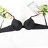 Black push-up bra styled with roses and lifestyle magazine on white surface