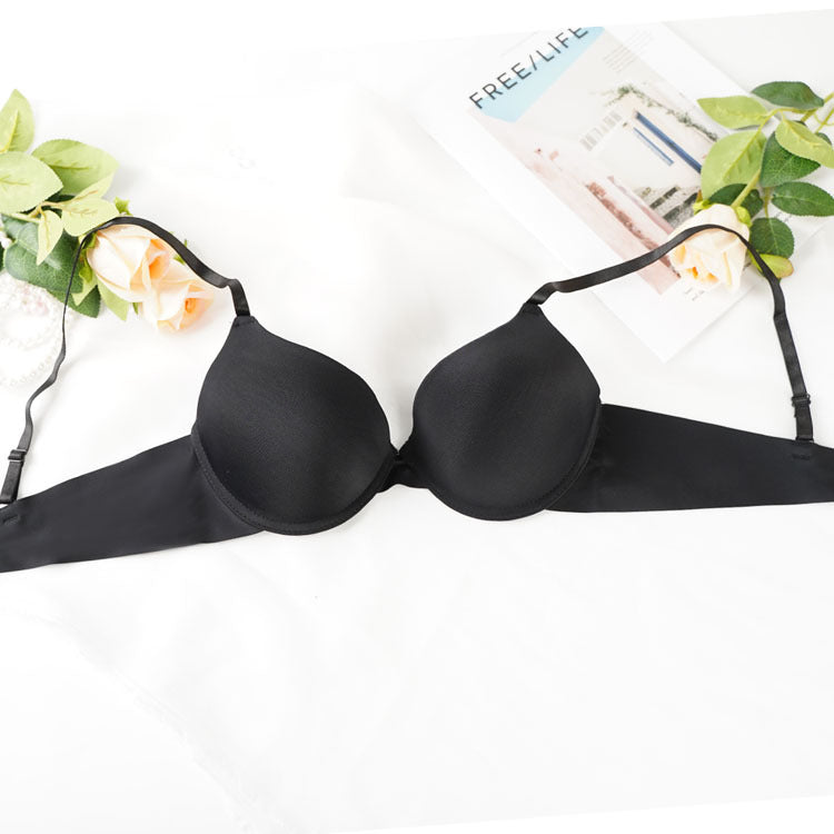 Black push-up bra styled with roses and lifestyle magazine on white surface