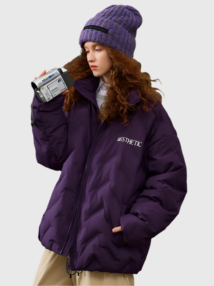 Woman holding vintage camcorder wearing purple Aesthetic puffer jacket with coordinating purple knit beanie and white sweater