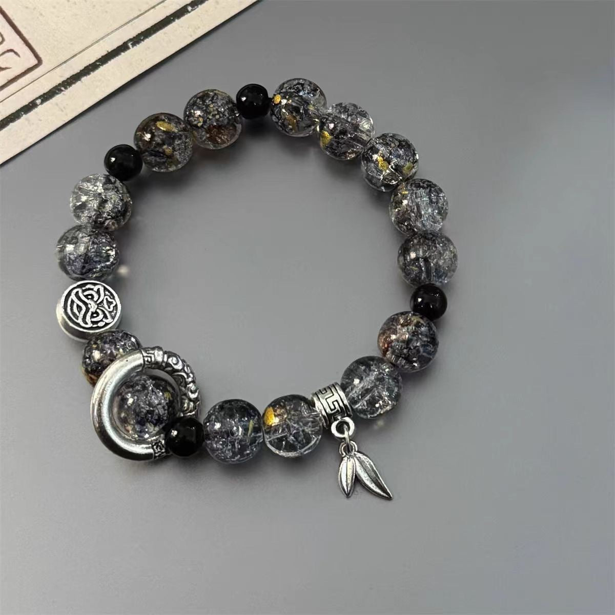 Crystal bracelet with gold flecks, featuring silver moon charm and leaf detail
