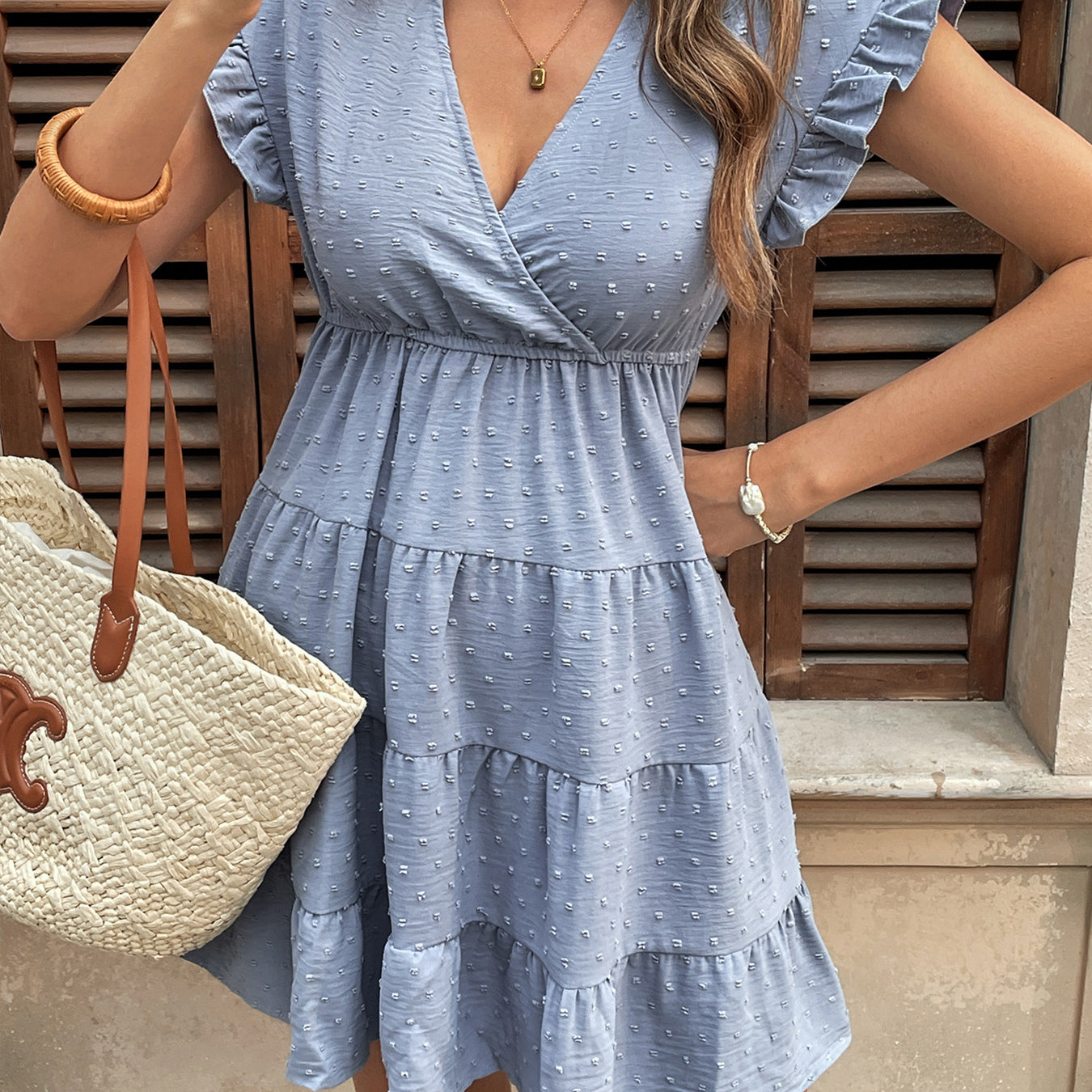 Woman taking a mirror selfie wearing a baby blue ruffle sleeve babydoll dress with a woven tote.