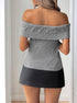 Back view of a woman in a gray off-shoulder ribbed top with fold-over detailing, styled with a black mini skirt.