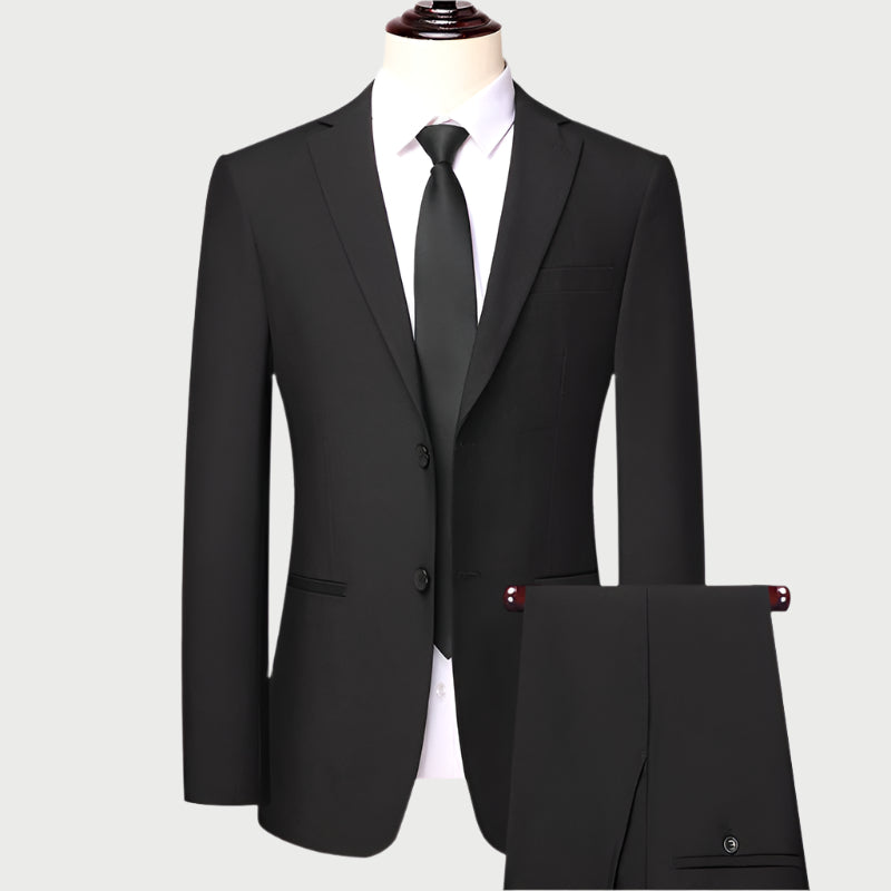 Black formal suit displayed on mannequin with white dress shirt and black tie, showing front view of single-breasted jacket with two buttons and matching trousers