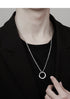Silver chain necklace with circular pendant worn with black outfit