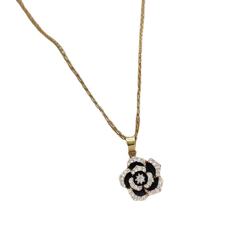 Close-up of gold chain necklace with black rose pendant featuring crystal-lined petals