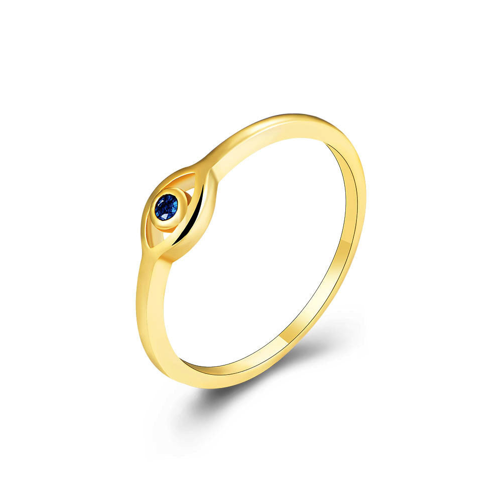 Angled view of gold ring with blue sapphire in stylized eye design on white background
