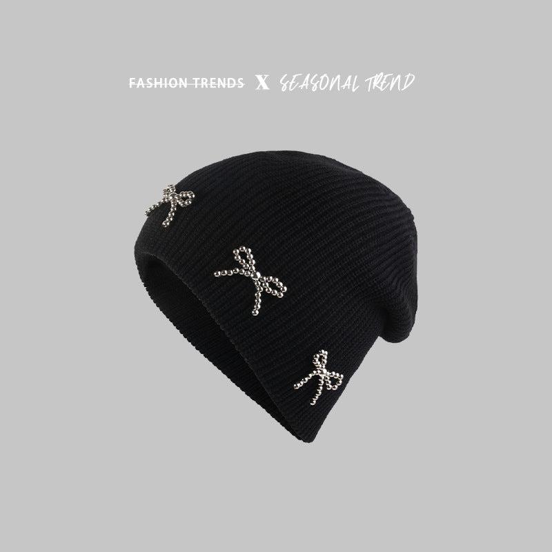 Black beanie with multiple pearl-studded bow decorations, displayed against a gray background with "Fashion Trends X Seasonal Trend" text