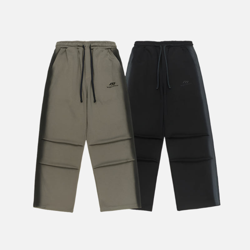 Two pairs of wide-leg sweatpants, one olive green and one black, both with drawstrings and subtle logo detailing