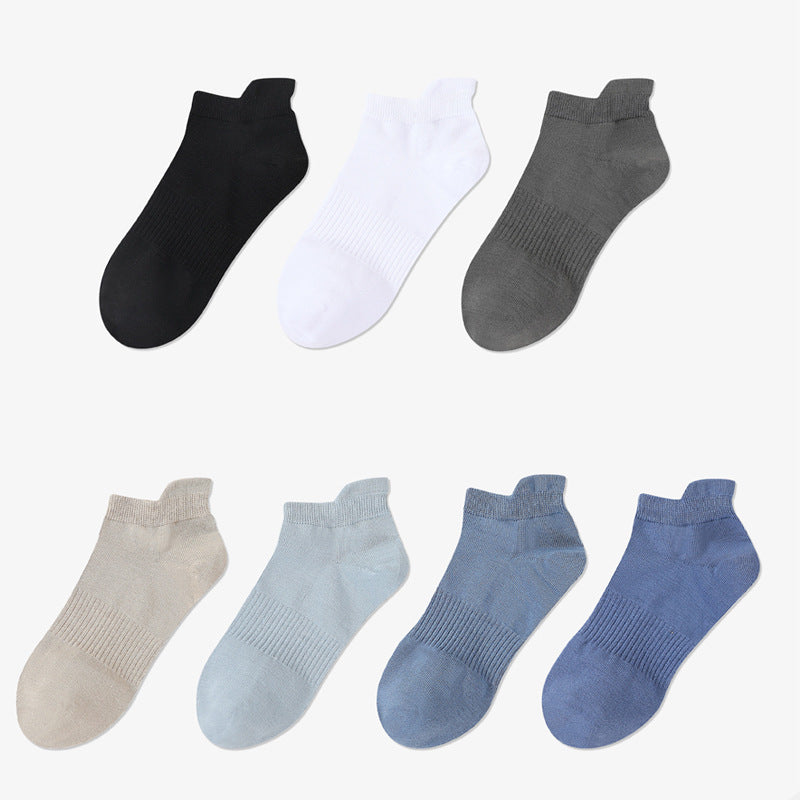 Seven pairs of ankle socks arranged in rows against white backdrop. Collection includes black, white, gray, beige, light blue and two shades of navy blue