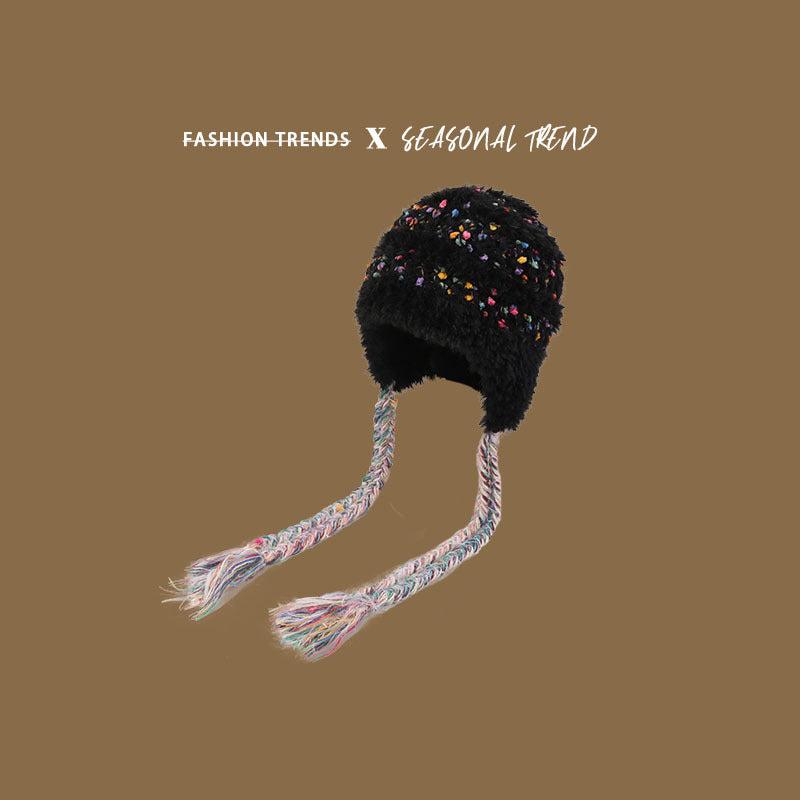 Black fuzzy winter hat with multicolored speckles and long braided earflaps, displaying seasonal accessory trend