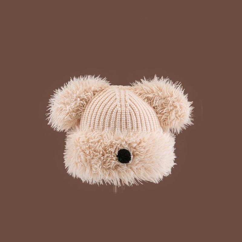 Beige Dog Nose Plush Knit Beanie with furry details against brown background, showing textural elements