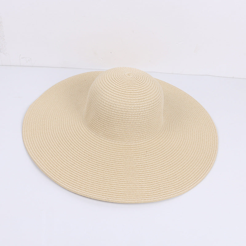 Beige wide-brimmed sun hat made of woven material, displayed on a white surface.