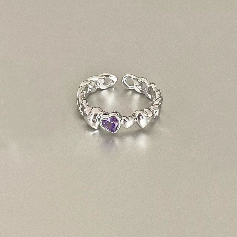 Silver adjustable chain ring with purple heart-shaped gemstone centerpiece displayed on light gray background, featuring delicate heart details