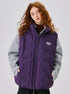 Model with auburn curly hair wearing purple down vest over gray sweater, turtleneck visible, Neightrainood brand logo, light gray background
