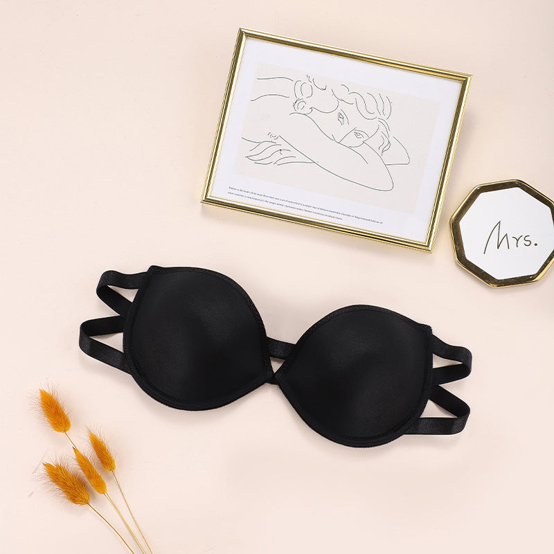 Black and ivory strapless bras laid flat, with gold-framed art print and "Mrs." decorative item