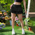 Full body shot of black ruffle mini skirt paired with crop top and white chunky sneakers in floral garden