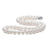 White pearl necklace laid in S-shape with silver clasp, displaying uniform round pearls