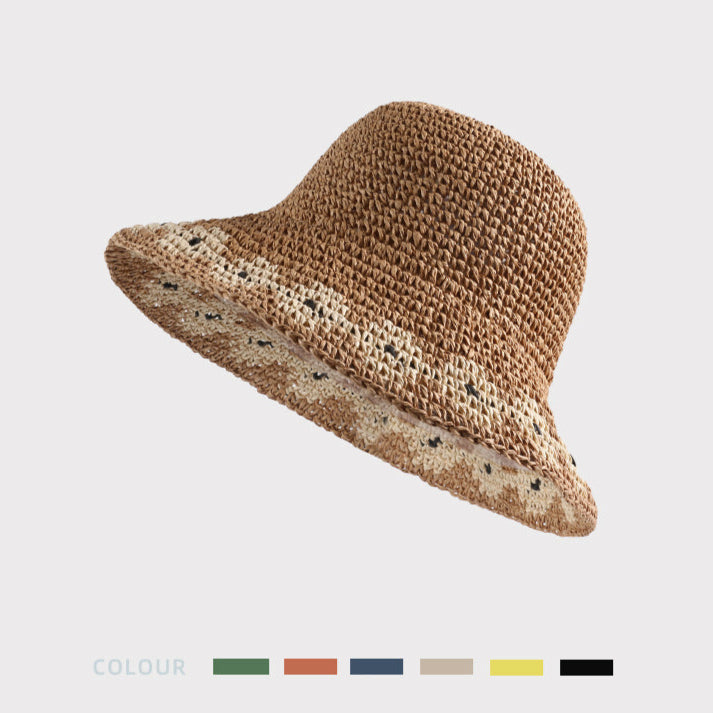  A close-up of a khaki woven bucket hat with a white floral pattern, tilted to highlight the textured design and intricate details.