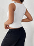 Back view of a woman wearing a white ribbed sleeveless crop top and high-waisted black pants, highlighting the fitted silhouette.