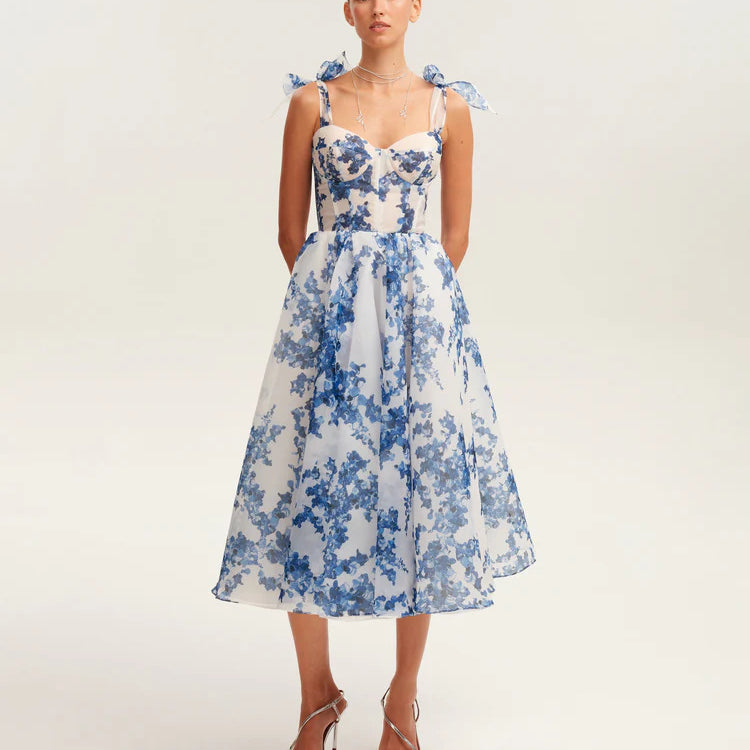 Front view of white and blue floral organza dress with bow shoulder straps and structured midi silhouette