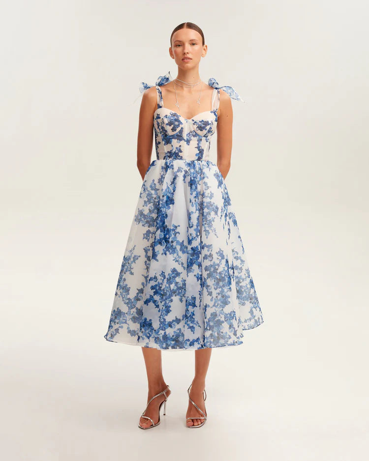 Front view of white and blue floral organza dress with bow shoulder straps and structured midi silhouette