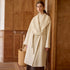 Full front view of cream wrap coat with oversized lapels on model