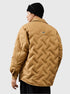 Back view of a man wearing black beanie and tan quilted jacket with diagonal pattern, showing brand logo patch