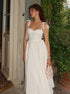 Woman in a white dress standing outside a building with greenery in the background