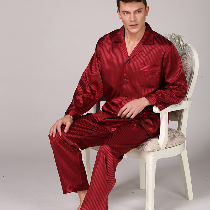 Man sitting in ornate white chair wearing burgundy striped silk pajamas with notched collar and relaxed long sleeves