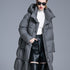 A woman wearing a gray puffer coat with white sweater and black leather skirt, hand in pocket, wearing sunglasses against gray background
