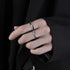 A hand wearing a silver textured ring, paired with a black outfit for a minimalist aesthetic.
