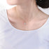 A woman wearing a white t-shirt with a gold Star of David necklace. The delicate pendant rests at her collarbone on a thin gold chain