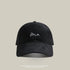 Black baseball cap with 'Me' embroidered in white cursive, featuring a curved brim and adjustable strap