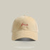 Khaki baseball cap with 'Me' embroidered in white cursive, washed fabric, and adjustable back strap