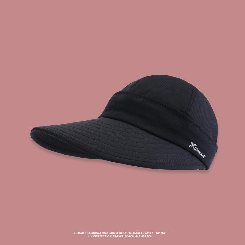 A black wide-brim foldable sun visor with UV protection and subtle brand logo displayed against pink background