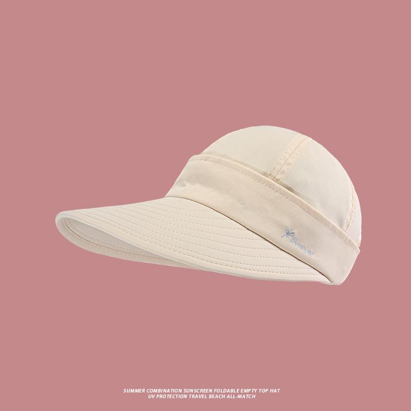 A cream colored foldable beach hat with wide UV protection brim and small logo embroidery against rose-colored background