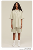 Woman with curly hair modeling cream oversized T-shirt and shorts set with white sneakers and silver chain necklace