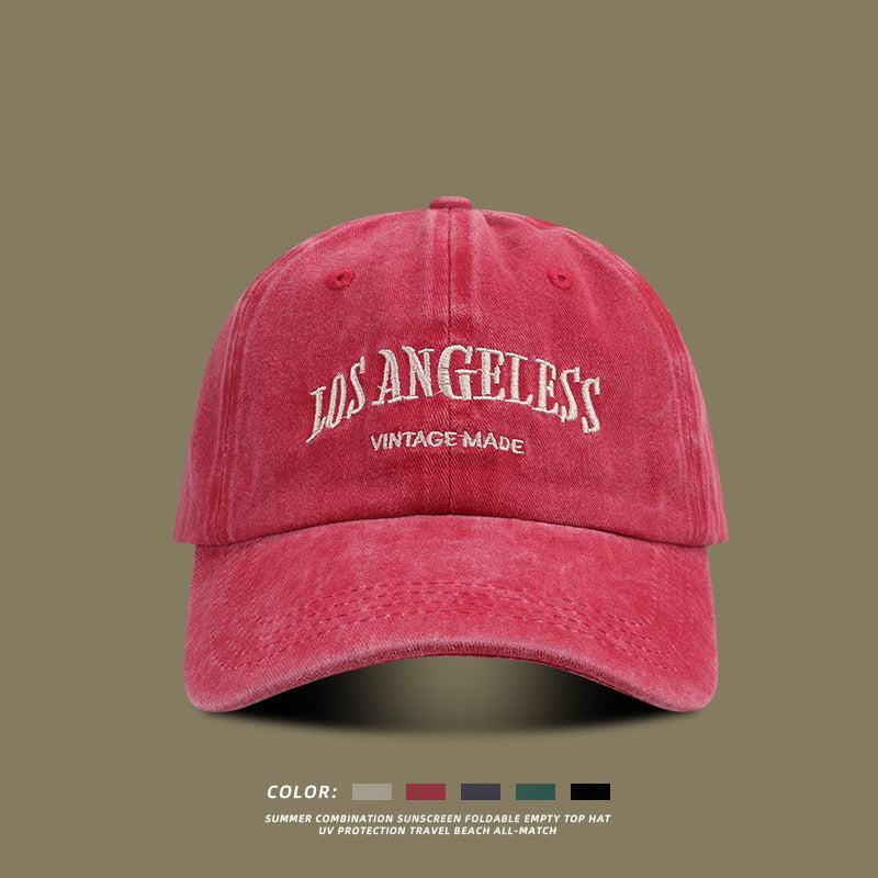 Red washed cotton baseball cap with white 'LOS ANGELES VINTAGE MADE' embroidery on front against neutral background