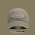 Beige washed cotton baseball cap with white 'LOS ANGELES VINTAGE MADE' embroidery on front against olive background