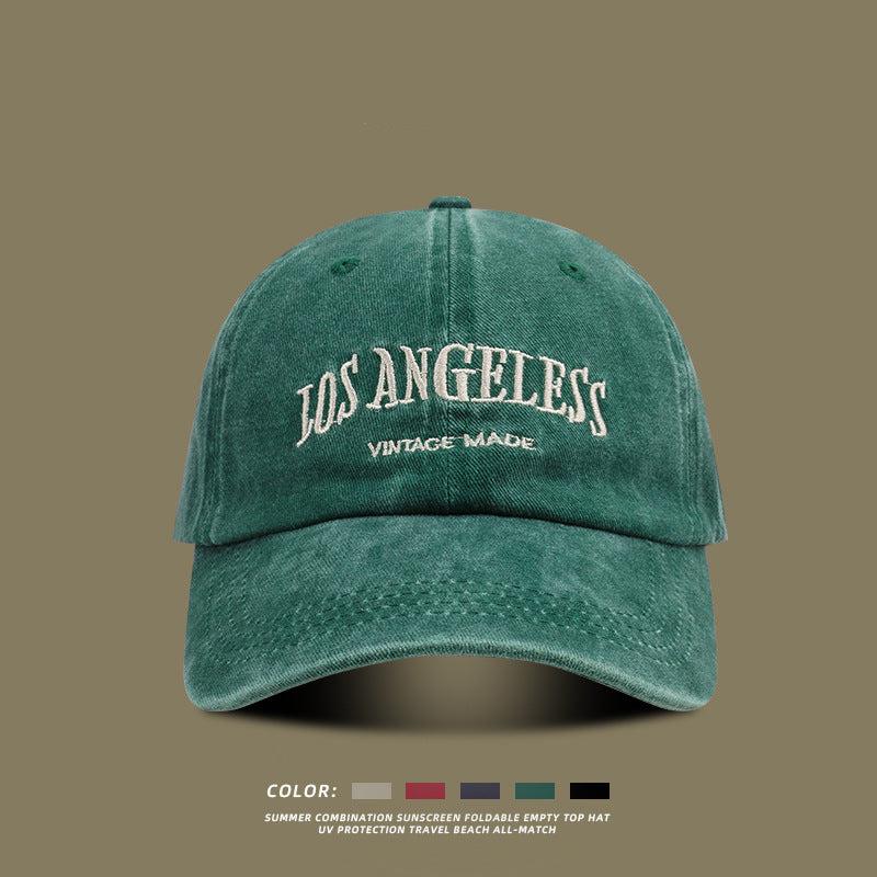 Forest green washed cotton baseball cap with white 'LOS ANGELES VINTAGE MADE' embroidery displayed on olive background